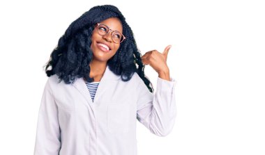 Güzel Afro-Amerikan gözlüklü, optometri gözlüklü, gülümseyen, gülümseyen ve baş parmağıyla yüzünü gösteren bir kadın.. 