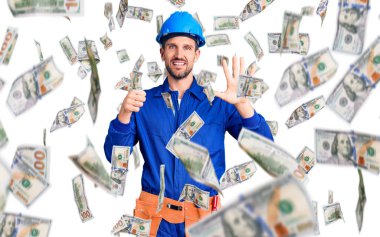 Genç, yakışıklı, işçi üniforması giyen, kasketli, altı numaralı parmaklarıyla işaret eden, kendinden emin ve mutlu bir şekilde gülümseyen bir adam..