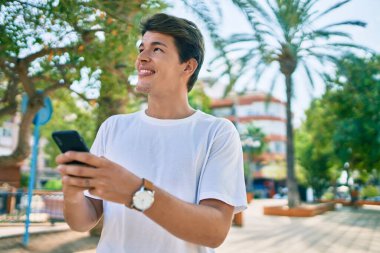 Beyaz adam şehirde akıllı telefon kullanarak mutlu bir şekilde gülümsüyor..