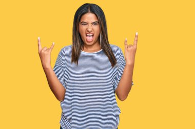 Gündelik kıyafetler giyen, çılgın bir ifadeyle bağıran genç Latin kız elleri havada rock sembolü yapıyor. Müzik yıldızı. ağır kavram. 