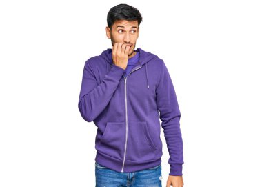 Günlük kazak giyen genç yakışıklı adam gergin ve gergin görünüyor. Ağzı tırnak yiyen eller. anksiyete. 