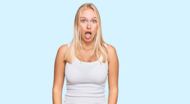 Kolsuz tişörtlü, sıradan giyinen genç sarışın kız şaşkınlık ve şaşkınlık dolu bir ifade, korku ve heyecanlı bir yüz ifadesiyle şoka uğradı.. 