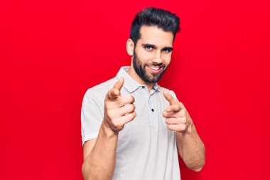 Sıradan polo giyen sakallı genç yakışıklı adam mutlu ve komik yüzüyle kamerayı işaret ediyor. iyi enerji ve titreşimler. 
