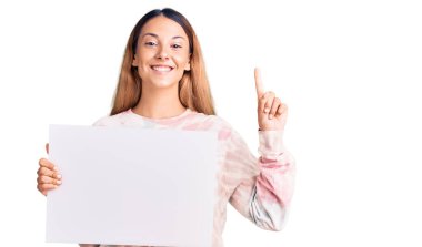 Elinde boş pankart tutan güzel genç bir kadın bir fikre ya da soru işaretine şaşırdı. 