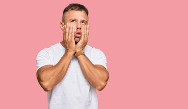 Yakışıklı, beyaz tişört giyen, yüzü, depresyonu ve üzüntüyü örten kaslı bir adam. 