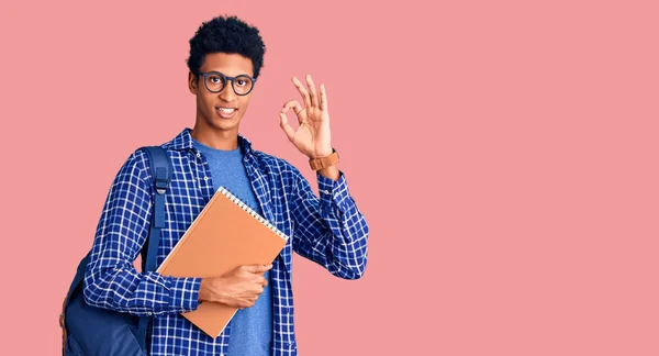 Joven Hombre Afroamericano Con Mochila Estudiante Sosteniendo Libro Sonriendo Positiva —  Fotos de Stock