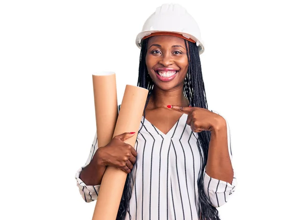 年轻的非洲裔美国女人戴着建筑师的硬礼帽 手里拿着设计图 高兴地微笑着 手指手画脚 — 图库照片