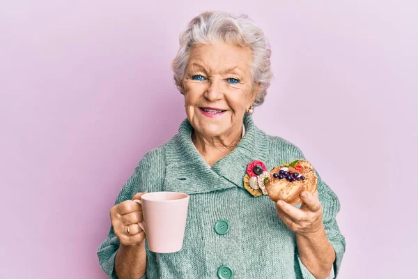 Oudere Grijsharige Vrouw Drinkt Een Kop Koffie Eet Broodjes Glimlachend — Stockfoto