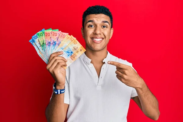 Joven Árabe Sosteniendo Billetes Franco Suizos Sonriendo Feliz Señalando Con —  Fotos de Stock