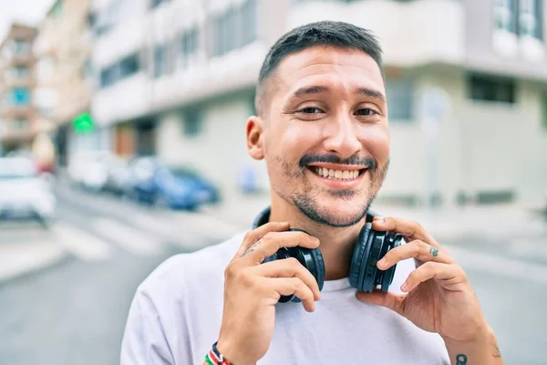 Ung Latinamerikansk Man Ler Glad Lyssnar Musik Med Hörlurar Gatan — Stockfoto