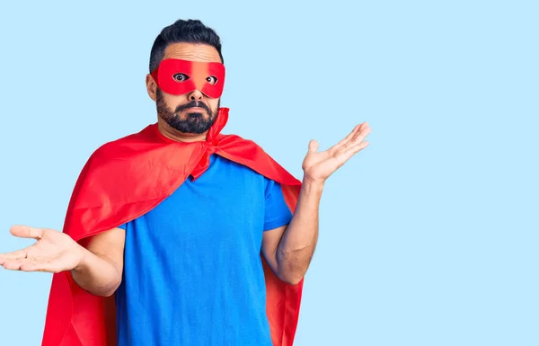スーパーヒーローの衣装を身に着けている若いヒスパニック系の男は 腕や手と無謀かつ混乱表現を調達しました 疑わしい概念 — ストック写真