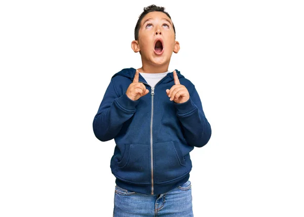 子供のヒスパニック子供を着てカジュアルなスポーティーなジャケット驚きと驚きを見て指と上げ腕で指差す — ストック写真