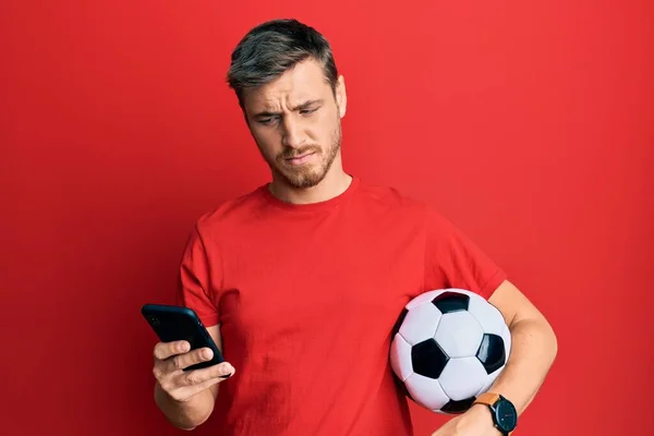 Snygg Kaukasisk Man Som Håller Fotboll Tittar Smartphone Chockansikte Ser — Stockfoto