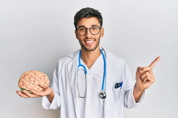 Jovem Bonito Homem Vestindo Médico Casaco Segurando Cérebro Sorrindo Feliz — Fotografia de Stock