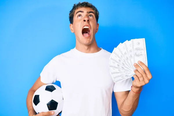 Joven Hombre Guapo Sosteniendo Pelota Fútbol Billetes Dólares Enojado Loco —  Fotos de Stock