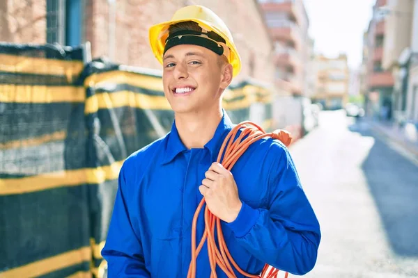 他的年轻同事笑着高兴地拿着电缆在城市的街道上 — 图库照片
