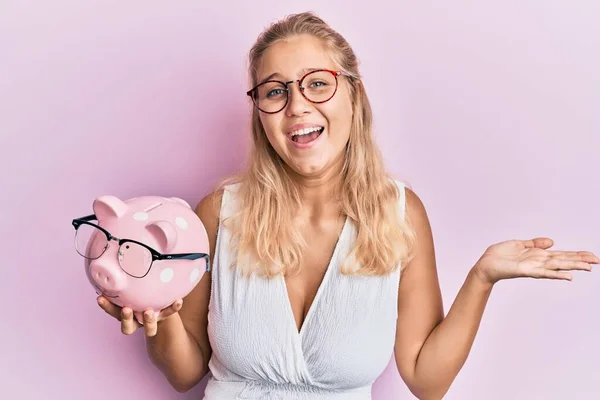 Jong Blond Meisje Holding Piggy Bank Met Bril Vieren Overwinning — Stockfoto