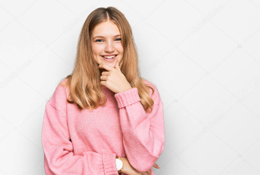 Beautiful young caucasian girl wearing casual winter sweater looking confident at the camera smiling with crossed arms and hand raised on chin. thinking positive. 