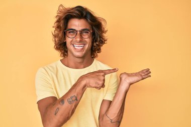 Gündelik kıyafetler giyen ve gözlüklü genç İspanyol adam kameraya hayret ediyor ve gülümsüyor.. 