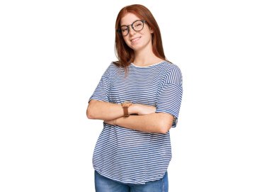 Gündelik kıyafetler ve gözlük takan, kolları çapraz gülümseyen ve kameraya bakan genç, okumuş bir kadın. pozitif kişi. 