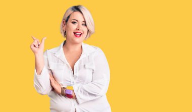 Genç sarışın ve cüsseli bir kadın. Sıradan bir gömlek giyiyor. Yüzünde kocaman bir gülümseme var.. 