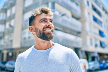 Genç İspanyol adam gülümseyerek şehirde mutlu bir şekilde yürüyor.