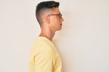 Gündelik kıyafetler ve gözlük takan genç İspanyol çocuk yanına bakıyor, rahat poz veriyor kendine güvenen bir gülümsemeyle doğal bir yüz ifadesi takınıyor.. 