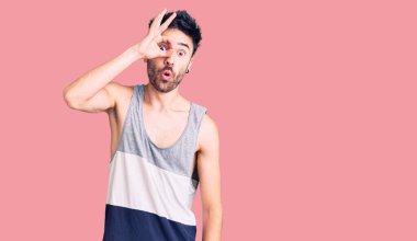 Gündelik kıyafetler giyen genç İspanyol adam şaşırmış yüz ifadesiyle şok olmuş, parmaklarından bakan gözler. İnançsız ifade. 