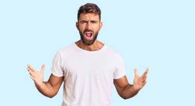 Latin asıllı genç bir adam, günlük beyaz tişört giyiyor. Deli gibi bağırıyor, agresif bir ifadeyle bağırıyor ve kollarını kaldırıyor. hüsran kavramı. 