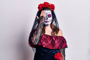 Genç bir kadın ölü kostümünü beyazın üstüne giyer. Bir gözünü eliyle kapatır. Yüzünde kendine güvenen bir gülümseme ve şaşırtıcı bir duygu vardır.. 