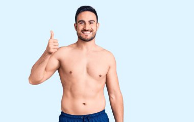 Young handsome man wearing swimwear smiling happy and positive, thumb up doing excellent and approval sign 