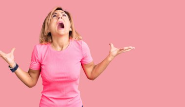 Spor kıyafetleri giyen genç sarışın kadın deli gibi bağırıyor ve bağırıyor agresif bir ifade ve kollar havada. hüsran kavramı. 