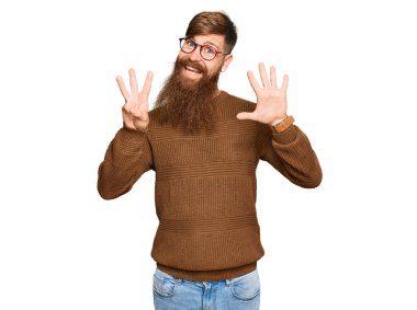 Genç İrlandalı kızıl elbiseli ve gözlüklü adam 8 numaralı parmaklarını gösterip işaret ederken kendinden emin ve mutlu gülümsüyor.. 