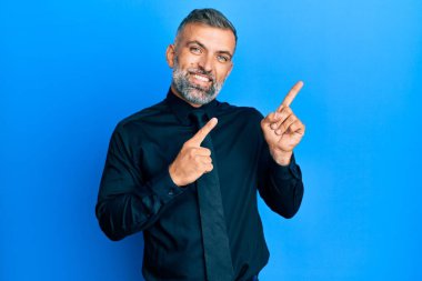 Orta yaşlı, iş gömleği ve kravat takan, gülümseyen ve kameraya bakan yakışıklı bir adam.. 