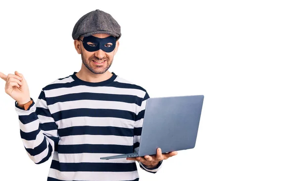 Young Handsome Man Wearing Burglar Mask Using Laptop Smiling Happy — Stock fotografie