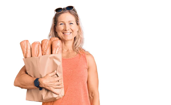 Medelålders Passform Blond Kvinna Håller Papperspåse Med Bröd Ser Positiv — Stockfoto