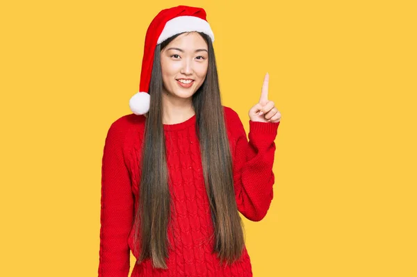 Young Chinese Woman Wearing Christmas Hat Pointing Finger Successful Idea — Stock Photo, Image