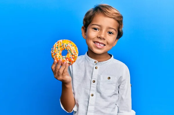 Очаровательный Латиноамериканец Держит Пончик Выглядит Позитивно Счастливо Стоя Улыбаясь Уверенной — стоковое фото