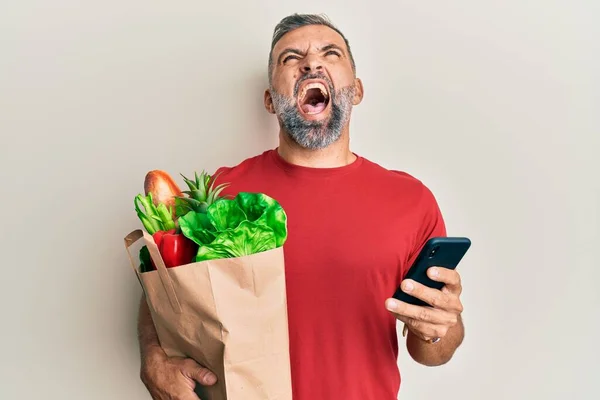 Hombre Guapo Mediana Edad Sosteniendo Bolsa Comestibles Usando Teléfono Inteligente —  Fotos de Stock