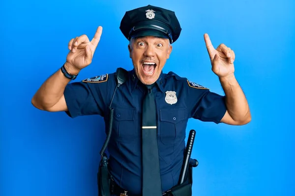 Handsome middle age mature man wearing police uniform smiling amazed and surprised and pointing up with fingers and raised arms.