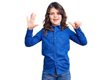 Uzun saçlı, günlük kıyafetler giyen, altı numaralı parmaklarıyla işaret eden sevimli çocuk, kendinden emin ve mutlu gülümsüyor.. 