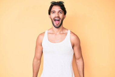 Yaz bakışı ve güneş gözlüğü takan yakışıklı İspanyol adam komik bir ifadeyle dilini dışarı çıkarıyor. duygu kavramı. 