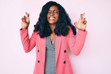 İş ceketi ve gözlük takan güzel Afrikalı kadın umut ve gözlerin kapalı gülümseyerek el sallıyor. Şans ve batıl inançlar. 