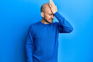 Hispanik kel bir adam günlük kışlık kazak giyiyor. Yan tarafa bakıyor, rahat bir poz veriyor ve kendine güvenen bir gülümseme takınıyor.. 