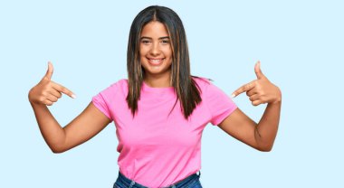 Gündelik kıyafetler giyen, kendine güvenen, gülümseyen, kendini gururlu ve mutlu gösteren genç bir Latin kız.. 