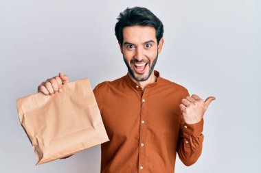 Elinde yiyecek tutan genç İspanyol adam başparmağını kaldırıyor ve ağzı açık gülümsüyor. 