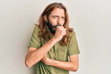 Uzun saçlı ve sakallı çekici bir adam günlük giysiler giyiyor kendini iyi hissetmiyor ve soğuk algınlığı veya bronşitin belirtisi olarak öksürüyor. sağlık hizmeti kavramı. 