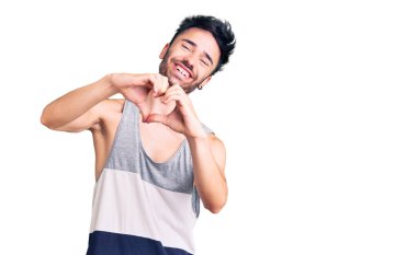 Gündelik kıyafetler giyen, aşık gülümseyen, elleriyle kalp sembolü yapan genç bir İspanyol. romantik kavram. 