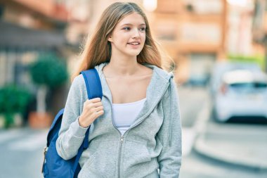 Güzel, beyaz bir genç, gülümsüyor, mutlu bir şekilde şehirde duruyor..