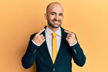 Hispanik kel adam iş elbisesi giyiyor ve stresten başı ağrıdığı için eli başının üstünde kravat takıyor. migren ağrısı. 